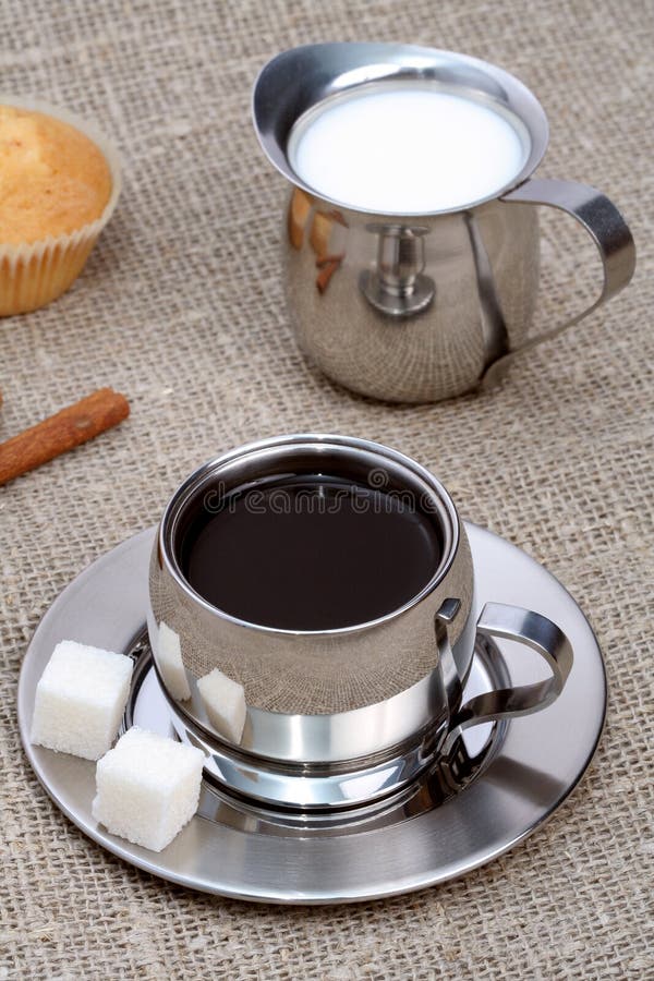 Cup of black coffee with muffin, milk and cinnamon