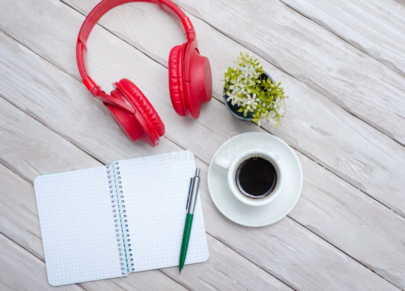 A cup of black coffee, overhead Musical headphones with a notepad with a blank page for text. Work desk with smartphone notepad stock image