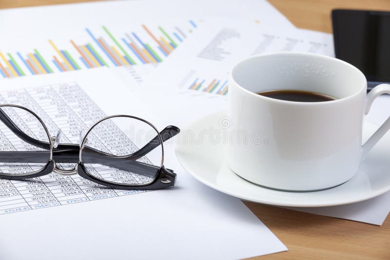 Cup of black coffee and spectacles on an accountant s desk