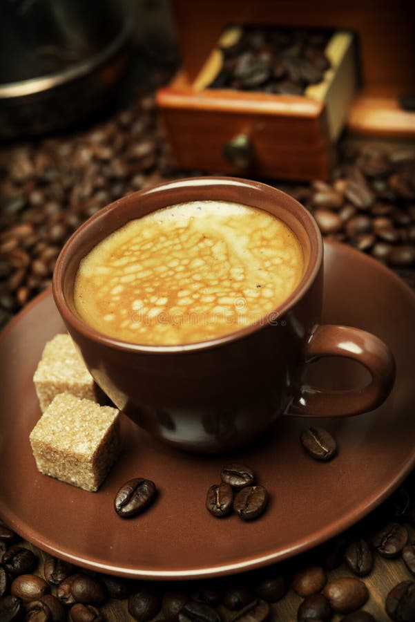 Cup of black coffee with sugar on the background of coffee beans