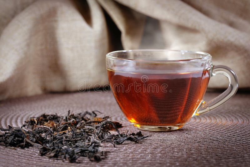 A Cup of Black Tea and Leaves on a Dark Background Stock Photo Image