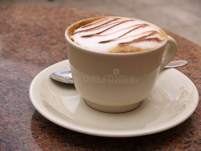 Close-up of a cup of coffee with the spoon, on ceramic plate