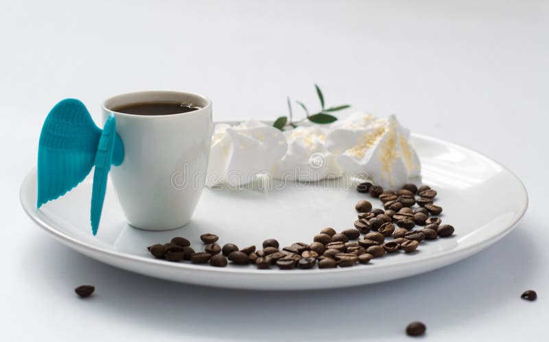 Cup coffee angel wings meringue beans plate white blossom espresso morning breakfast light royalty free stock image Cup coffee angel wings meringue beans plate white blossom espresso morning breakfast light royalty free stock image