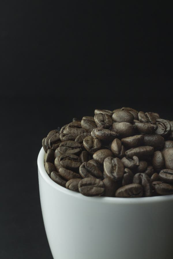 Cup of Black Coffee with Foam on Background of Roasted Coffee Beans