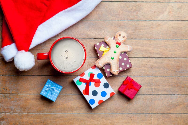 Cup of coffee, gifts, gingerbread man and santa claus hat on the