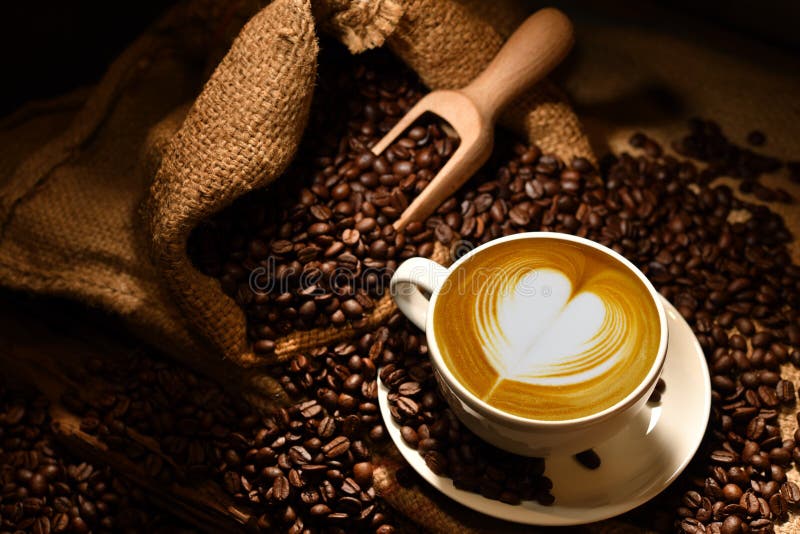 Cup of coffee latte with heart shape and coffee beans on old wooden background