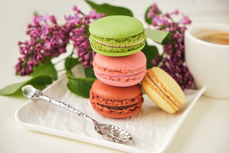 Cup of coffee with macaroons on a table with flowers