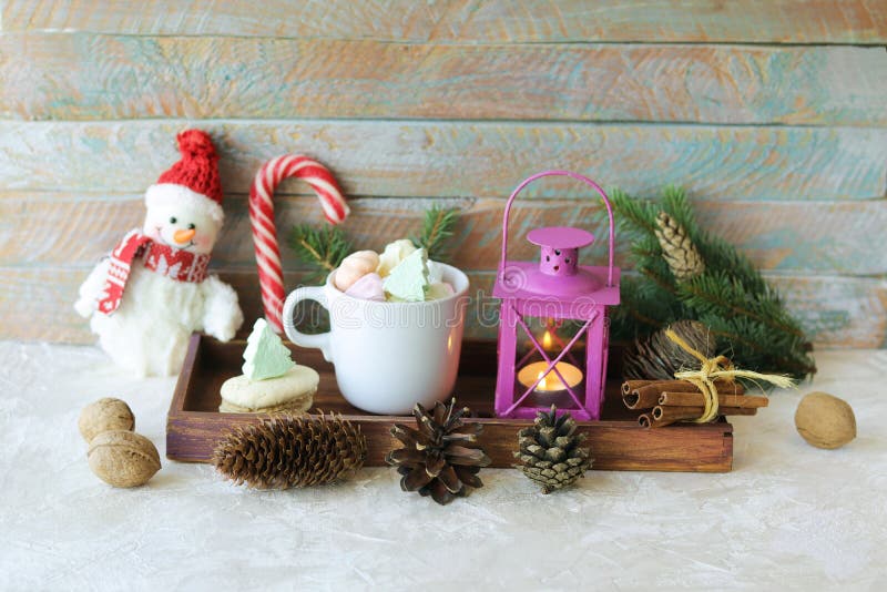 Cup of coffee with meringue and dessert, Christmas decor, snowman, lantern with a burning candle, on a wooden table, the concept o