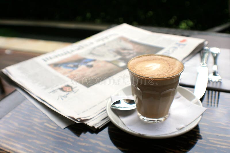 Cup of coffee with news paper on table
