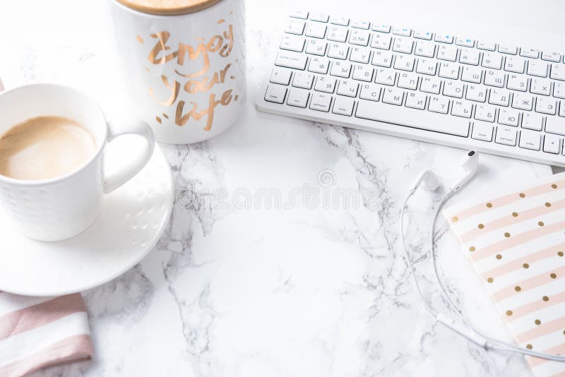 Cup of coffee, notepad and keyboard on white marble table