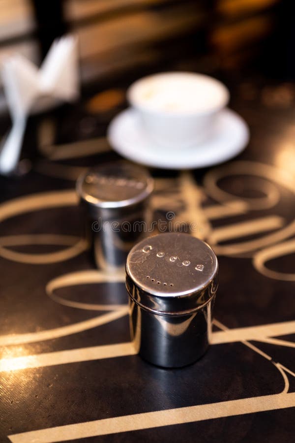 Cup of Coffee with Salt and Pepper Shaker on Table in Coffee Shop Cafe