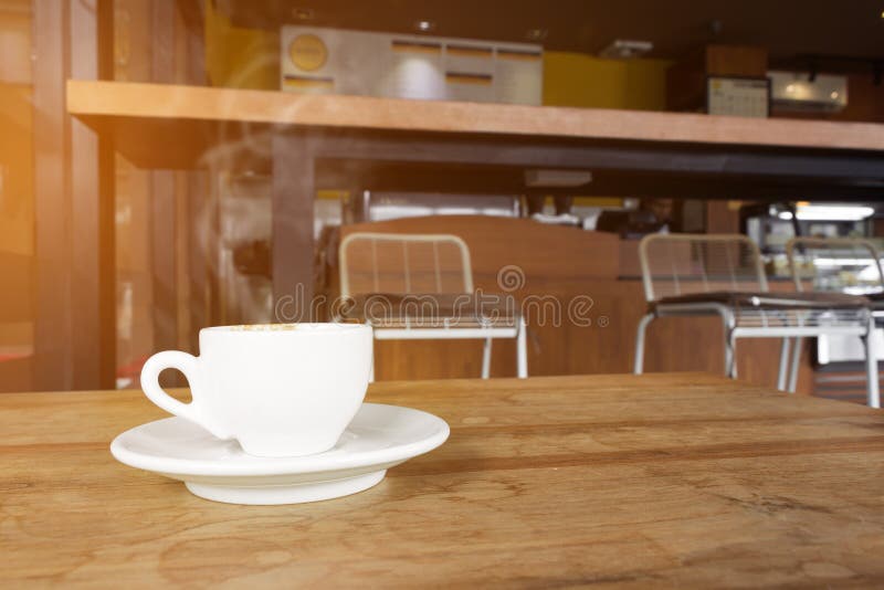 Cup of Coffee with Smoke on Wooden Table in Cafe. Stock Photo Image