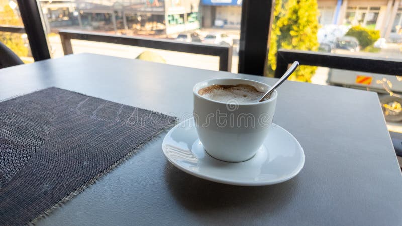 Cup of coffee with spoon on modern cafe table, morning light and relaxing lifestyle atmosphere royalty free stock image