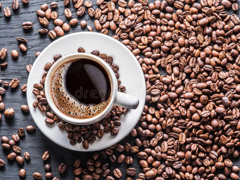 Cup of coffee surrounded by coffee beans. Top view. stock photography