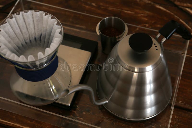 Cup with Coffee, Wave Dripper and Kettle on Wooden Table in Cafe Stock