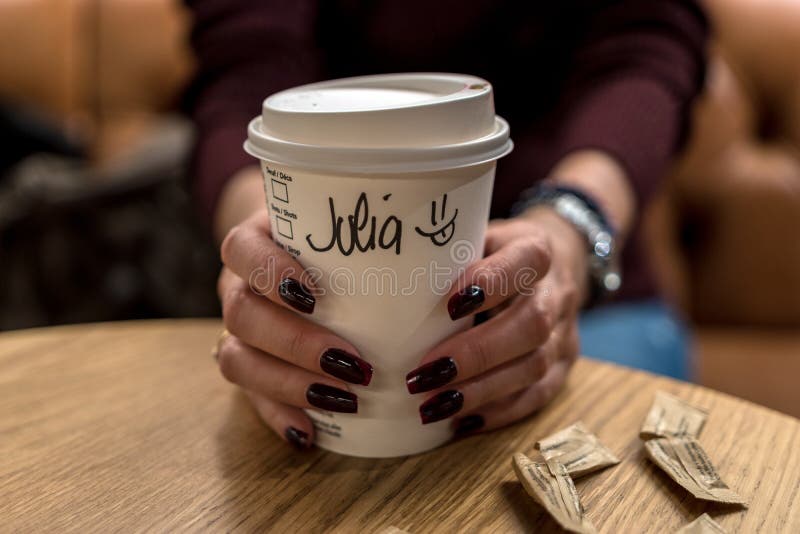 Cup of coffee with writen word JULIA in woman hand