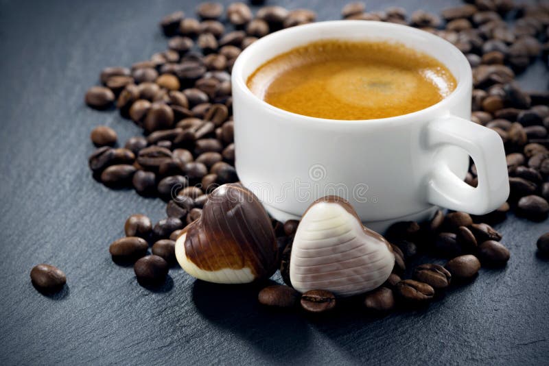 Cup of espresso, coffee beans background and chocolate candies