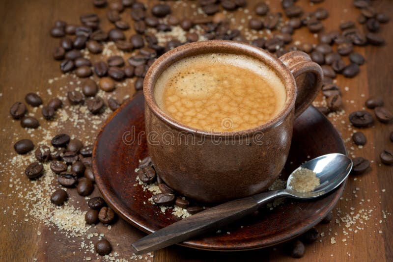 Cup of espresso, sugar and coffee beans on wooden table