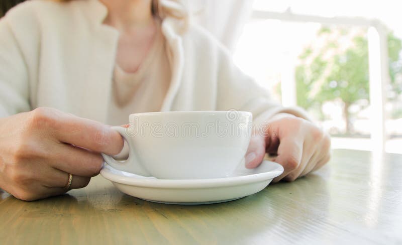 Cup of fresh cappuccino coffee in female hands on the table in summer cafe stock image Cup of fresh cappuccino coffee in female hands on the table in summer cafe stock image