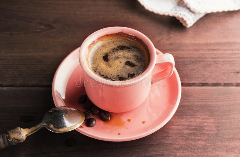 A cup of fresh coffee, just stirred with a spoon, stands on a wooden table. Concept of coffee, breakfast or break on a sunny day