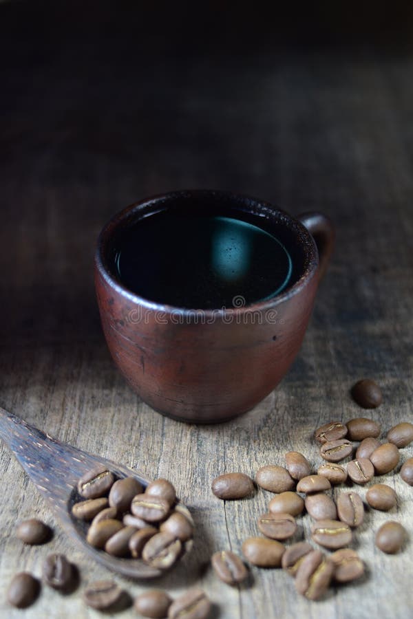 A cup of fresh coffee on old kitchen table. A scattering of coffee beans with a cup of coffee stock photography A cup of fresh coffee on old kitchen table. A scattering of coffee beans with a cup of coffee stock photography