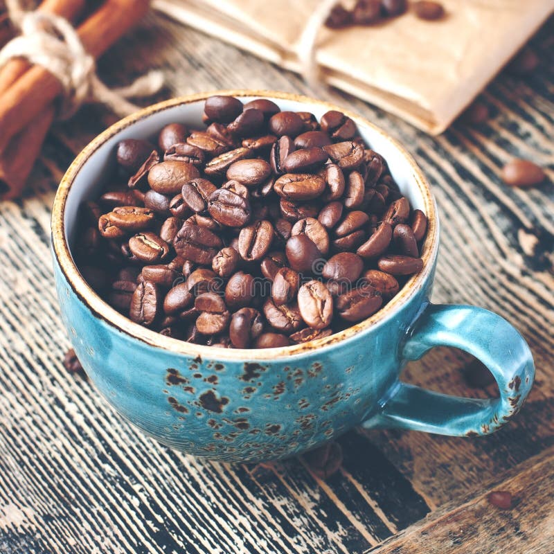 Cup full of coffee beans on wooden table