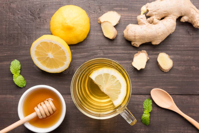 Cup of ginger tea with lemon and honey on wooden background