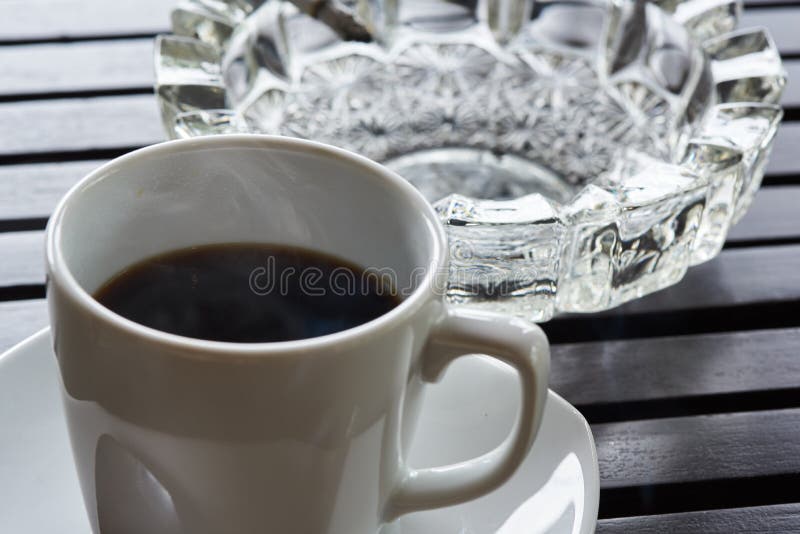 A cup of hot coffee and cigarette ashtray on the table stock photo A cup of hot coffee and cigarette ashtray on the table stock photo