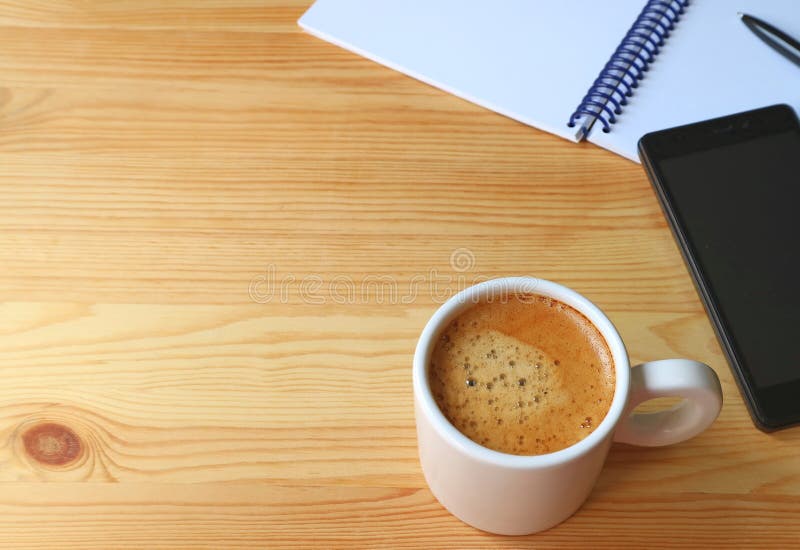 A Cup of Hot Coffee on Wooden Working Desk with Cellphone and Notebook stock images A Cup of Hot Coffee on Wooden Working Desk with Cellphone and Notebook stock images