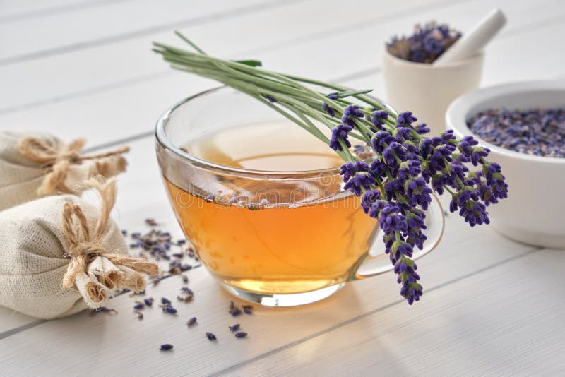 Cup of healthy lavender tea and lavender flowers. Mortars of dry lavender and sachets on background. Alternative medicine