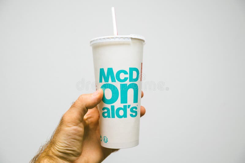 A cup of McDonald`s Cola with plastic straw inside restaurant