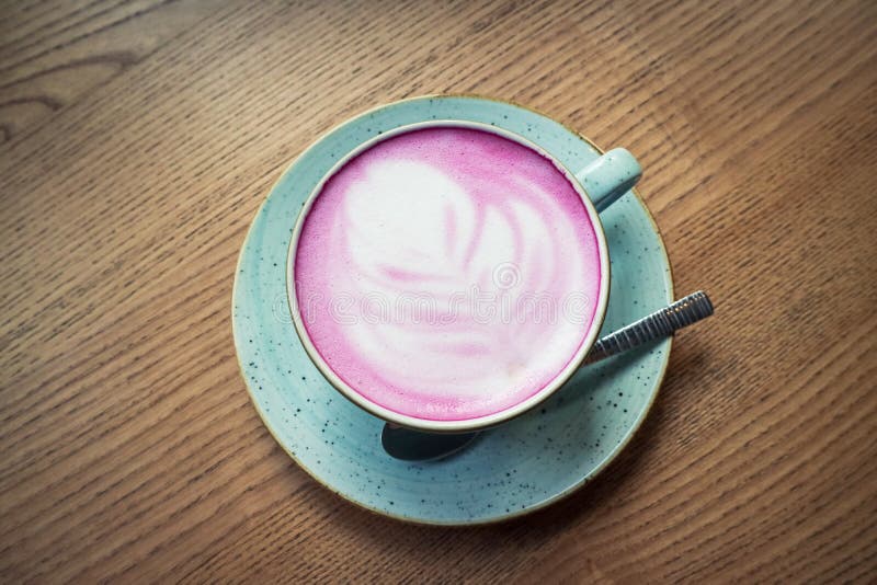 Cup of pink cappuccino in blue cup. 