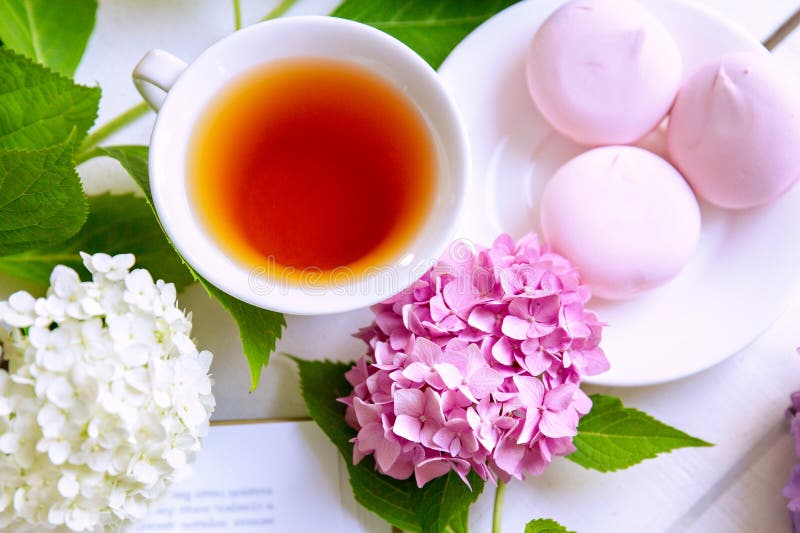 A Cup of Tea Surrounded by Hydrangea Flowers, with Pink Marshmallows