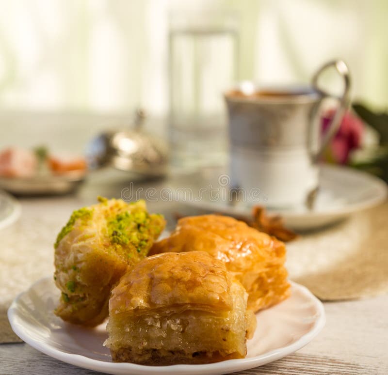 Cup of Turkish coffee and a plate with baklava. Napkin, arabic.