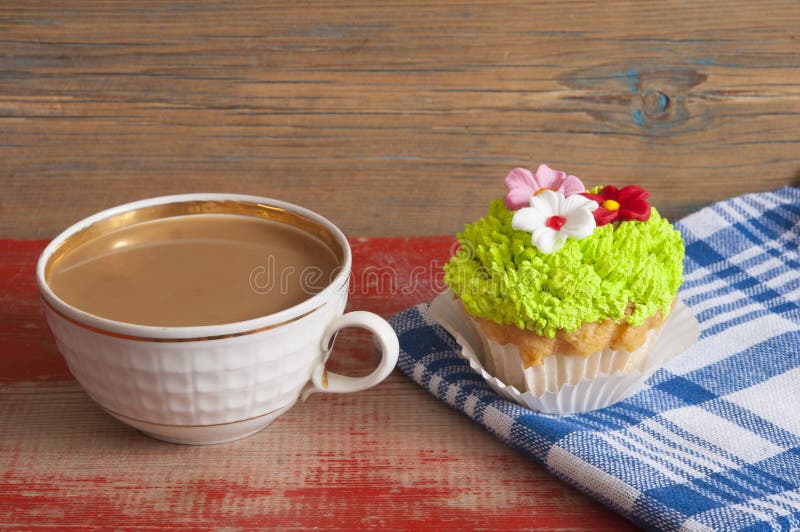 Flower spring cupcake with hot coffee cup on wooden table