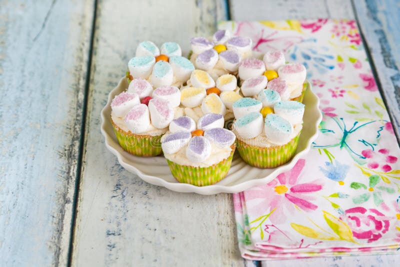 Cupcakes που διακοσμείται με τα βουτύρου λουλούδια κρέμας και marshmallow στοκ εικόνα με δικαίωμα ελεύθερης χρήσης Cupcakes που διακοσμείται με τα βουτύρου λουλούδια κρέμας και marshmallow στοκ εικόνα με δικαίωμα ελεύθερης χρήσης