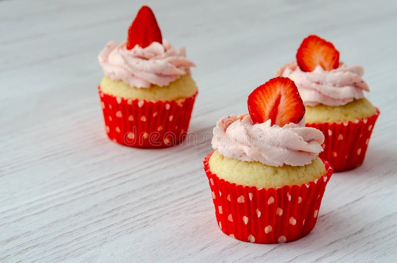 Cupcakes με τη διακόσμηση φραουλών σε ένα άσπρο ξύλινο υπόβαθρο στοκ φωτογραφία με δικαίωμα ελεύθερης χρήσης Cupcakes με τη διακόσμηση φραουλών σε ένα άσπρο ξύλινο υπόβαθρο στοκ φωτογραφία με δικαίωμα ελεύθερης χρήσης