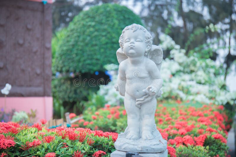 Cupid Stone Statue in the Flower Garden. Stock Photo Image of green
