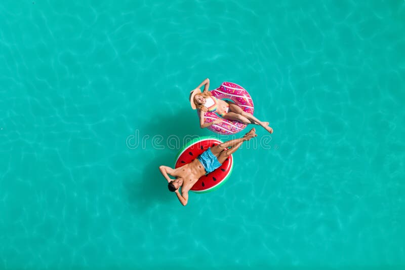 Cuplu fericit cu inele gonflabile în piscină. vacanță de vară stock photography