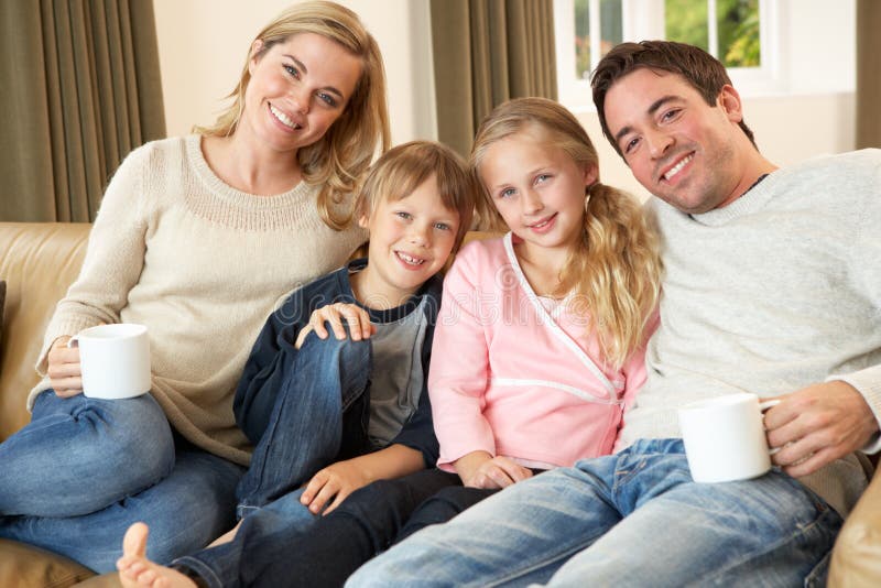 Happy young family sitting on sofa holding cups Smiling. Happy young family sitting on sofa holding cups Smiling
