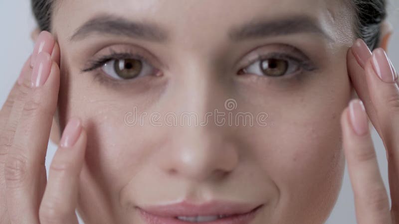 Cura del fronte Pelle commovente della donna attraente sotto il primo piano degli occhi