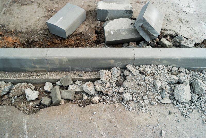 Curdstones che si trova sul marciapiede vicino al pozzo per l'installazione del confine Superficie rotta dell'asfalto dal lato Un fotografie stock Curdstones che si trova sul marciapiede vicino al pozzo per l'installazione del confine Superficie rotta dell'asfalto dal lato Un fotografie stock