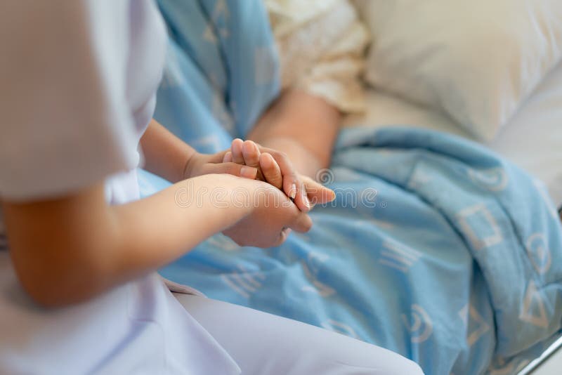 Curi la seduta su un letto di ospedale accanto alle mani amiche di una donna pi? anziana, concetto di assistenza agli'anziani