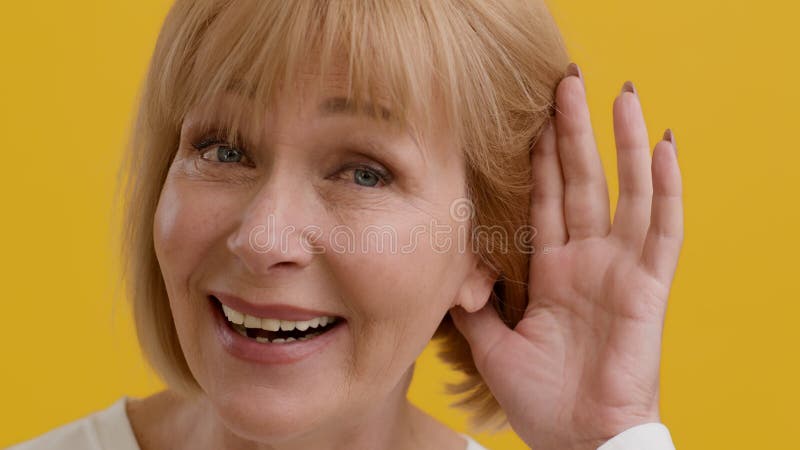 Curiosité féminine. une femme âgée excitée écoutant des commérages à la main près de l'oreille