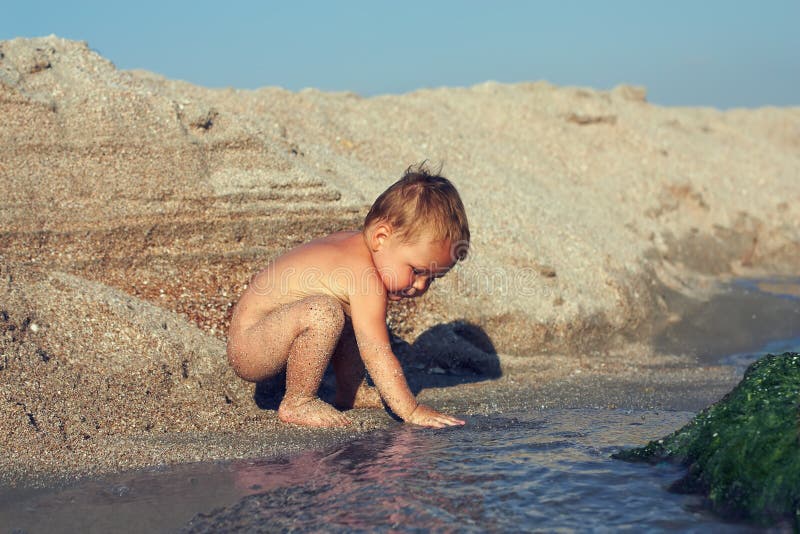 Curious baby boy playing with water stock photo