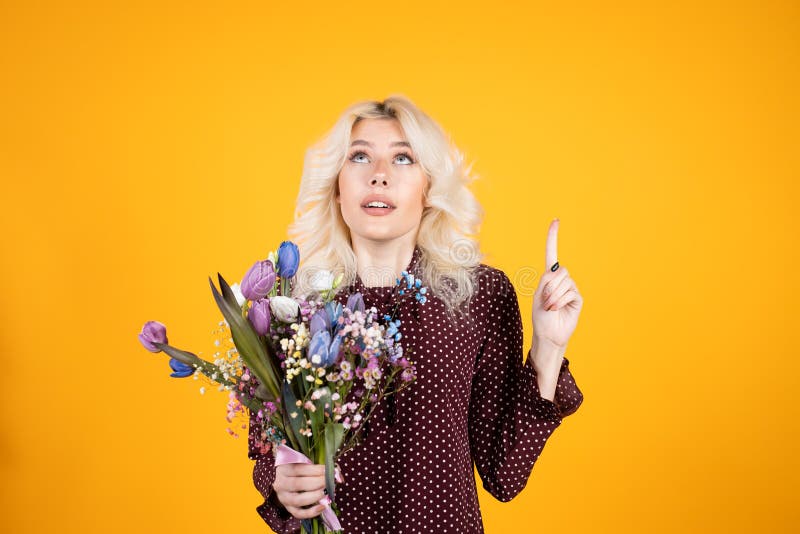 Curious Blonde Girl with Flowers Looking Up Isolated on Yellow ...