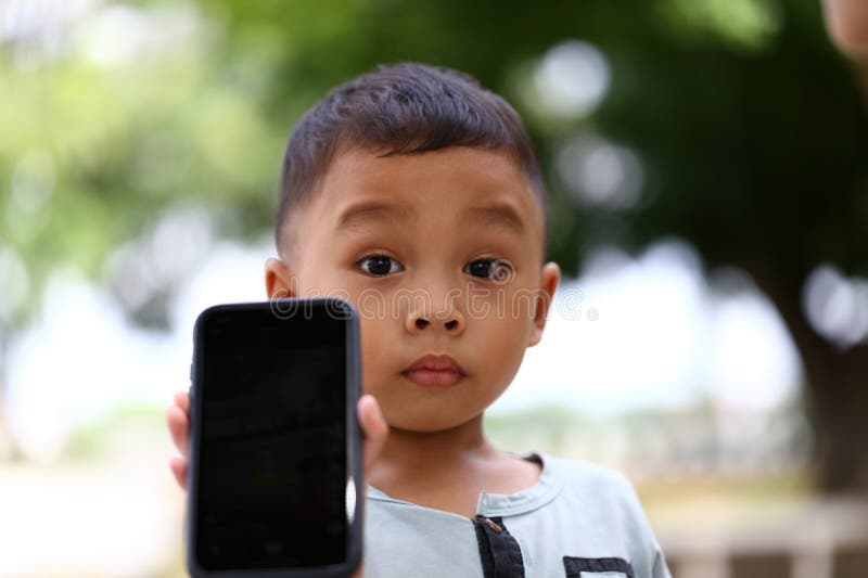 Curious Child Holding Smartphone Outdoors stock photos