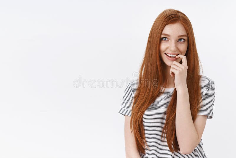 Curious intrigued lovely young romantic redhead girl blue eyes thouthfully biting finger smiling delighted imagine