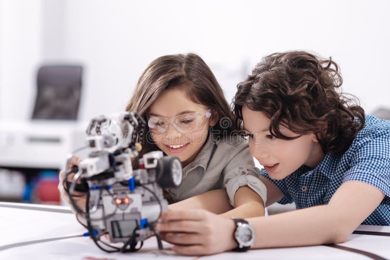 Curious kids playing with robot at school stock photography