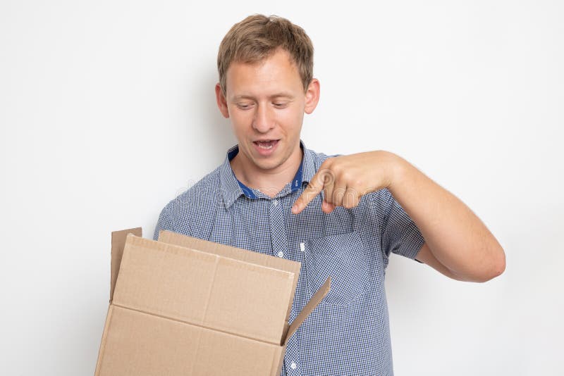curious man looking inside a cardboard box he holds in his hands on a white background